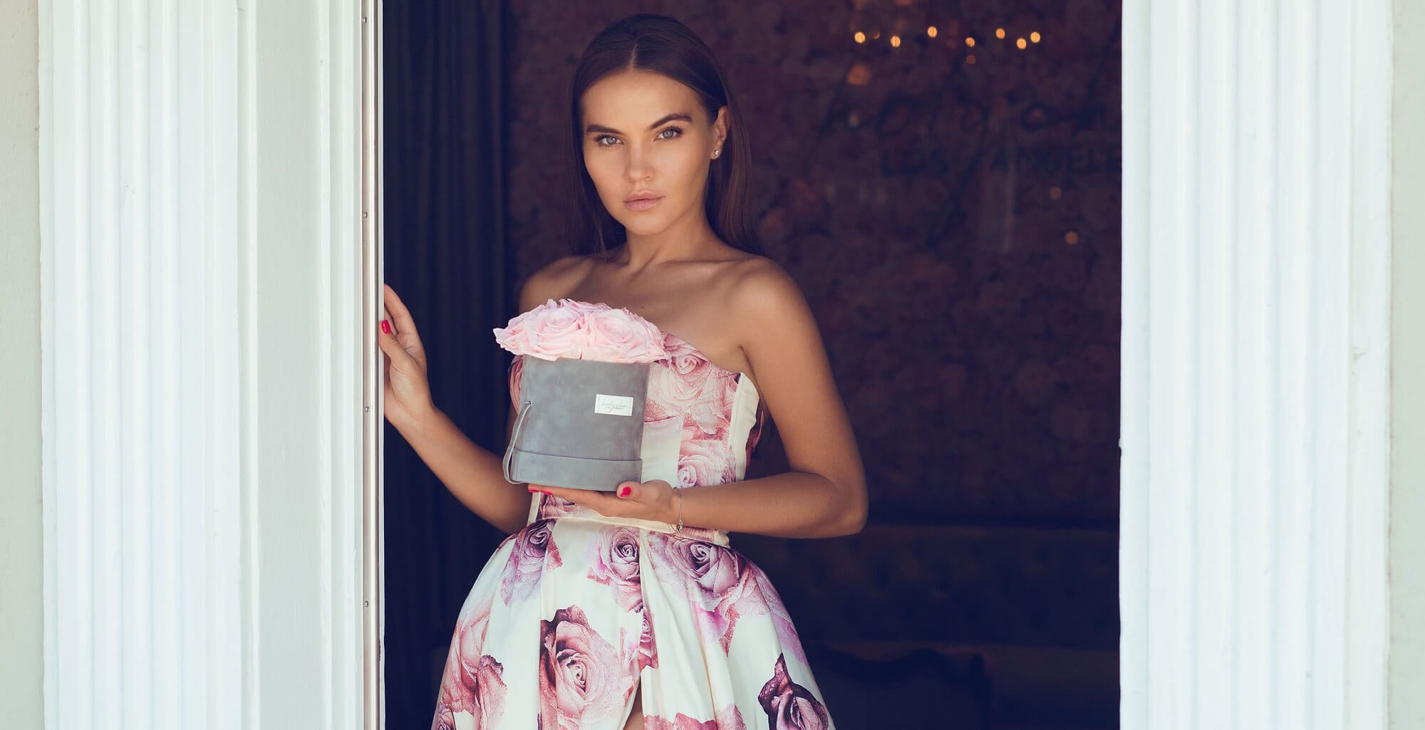 Girl in a dress holding a velvet round box with preserved roses in her hand
